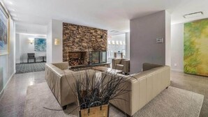 A modern living room with a stone fireplace, beige sofas, and a large abstract painting.