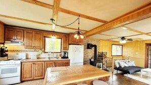 A spacious kitchen with wooden cabinets, a large island with stools, a stove, and a refrigerator.