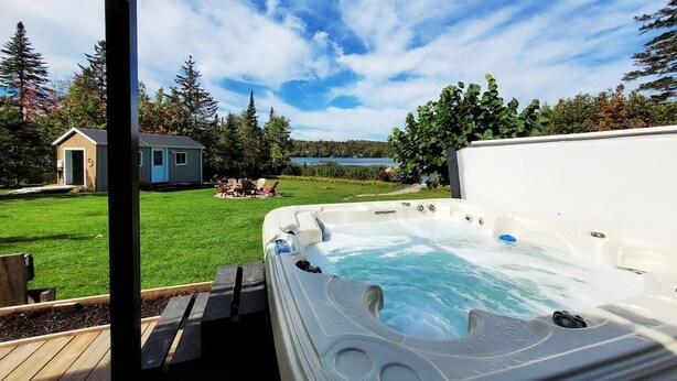A hot tub with a clear view of a lake and a house in the background.