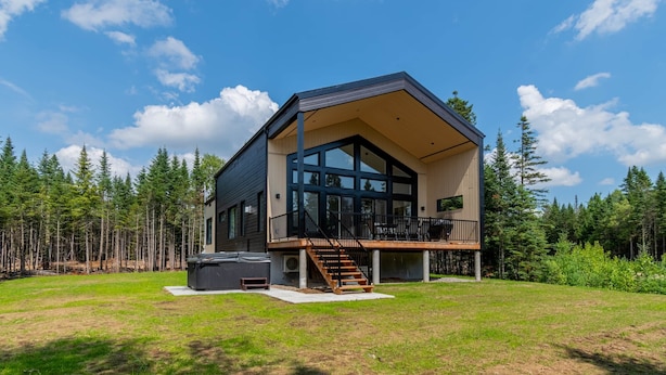 A modern two-story house with a large deck, surrounded by a forest. - Hôtel à la maison - Le Lys, nature et spa (Shannon)