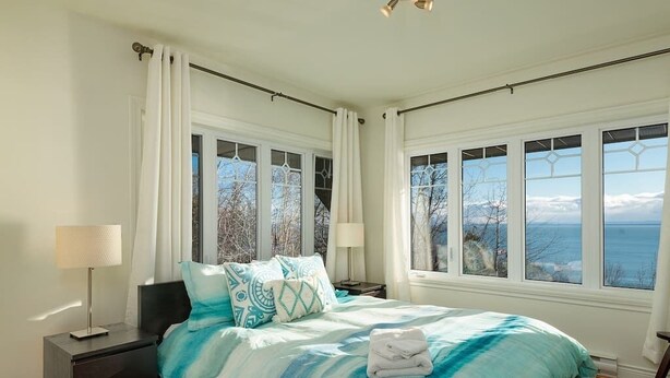 Une chambre avec un grand lit, deux tables de chevet, une commode et une vue sur la mer.