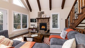 Una sala de estar acogedora con chimenea, ventanas amplias y una escalera.