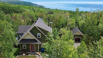A two-story house with a red door, a garage, and a view of a lake.