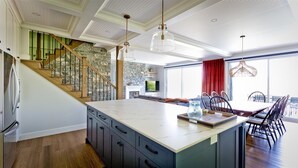 Una cocina amplia con una isla grande, un comedor con una cortina roja y una escalera de piedra.