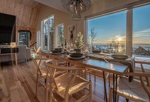 Uma sala de jantar com uma mesa grande, cadeiras e vista para o exterior.