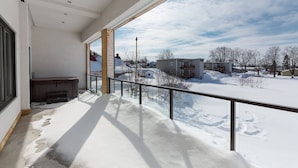 Un balcón con suelo cubierto de nieve, vistas a una zona residencial y un cielo despejado.