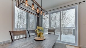 Ein Essbereich mit einem großen Holztisch, Stühlen und einer modernen Pendelleuchte.