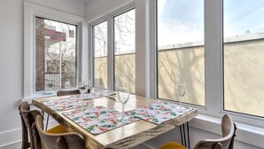 A dining area with a wooden table, floral placemats, and chairs. - Hôtel à la maison - Le Gaillard (Montreal)