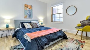 A bedroom with a bed, two bedside tables, a chair, a window, and a painting on the wall. - Hôtel à la maison - Le Gaillard (Montreal)