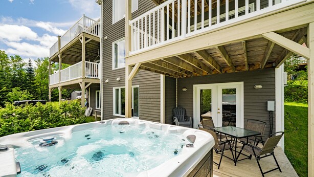 Een hottub op een houten terras, met een eethoek en een overdekt terras.