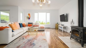 Een moderne woonkamer met een witte bank, kleurrijke kussens, een salontafel, een open haard en een televisie.