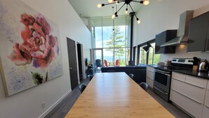 Una cocina moderna con una mesa de comedor de madera, un cuadro grande y vistas al exterior.