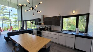Una cocina moderna con una mesa de comedor de madera, sillas negras y un horno empotrado.