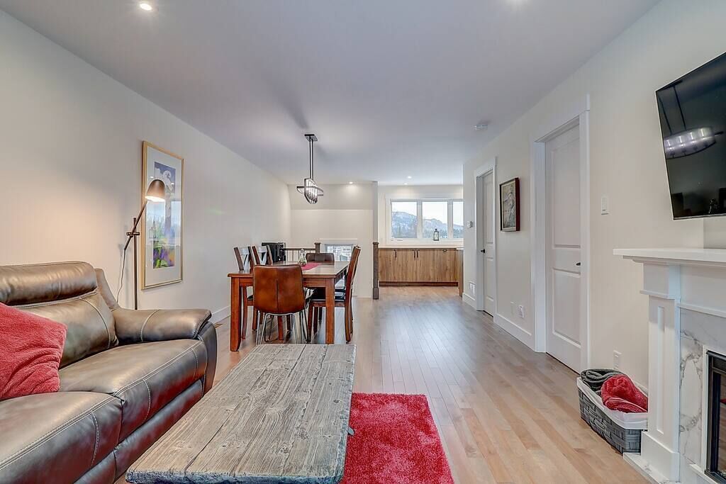 Una sala de estar moderna con un sofá de cuero, una mesa de comedor y sillas. Hay una chimenea y un televisor montado en la pared.