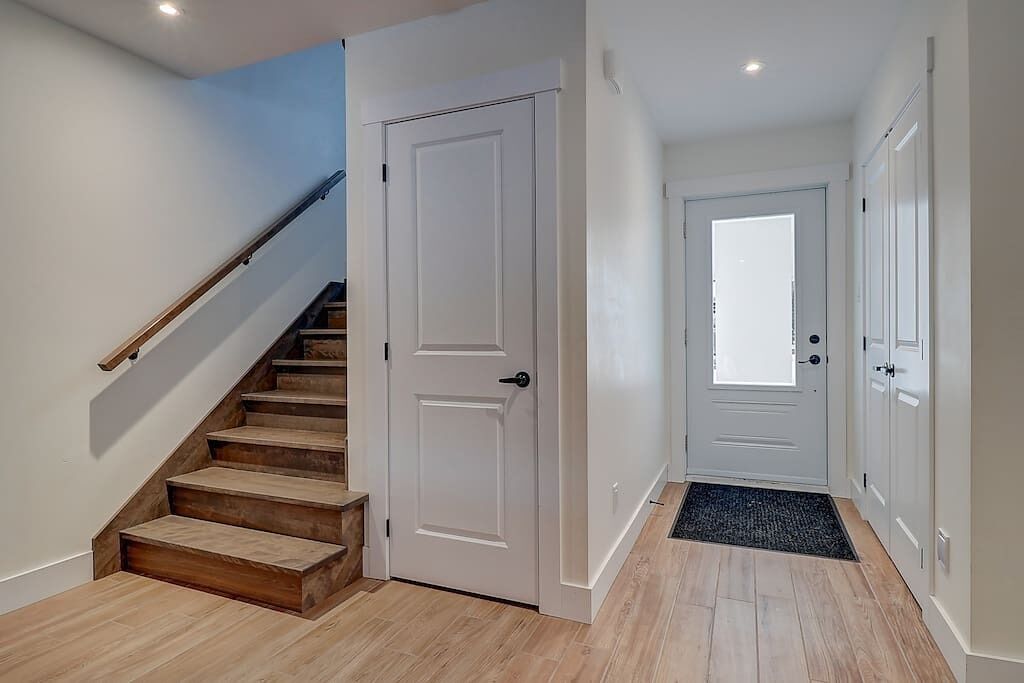 Un escalier avec des marches en bois menant à une porte blanche.
