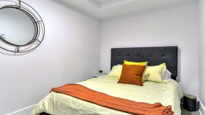 Ein Schlafzimmer mit einem Bett, einem runden Spiegel und einem dunklen Kopfteil.