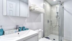 Ein modernes Badezimmer mit einem weißen Waschbecken, einer Duschkabine aus Glas und einem Handtuchhalter über der Toilette.