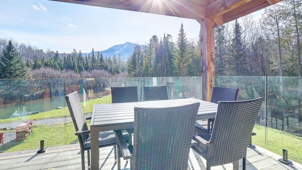 Un espace extérieur abrité où l’on peut prendre ses repas, avec vue sur un lac et des montagnes.