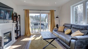 Un salon moderne doté d’une cheminée, d’un canapé en cuir et d’une grande fenêtre donnant sur l’extérieur.