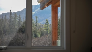 Une fenêtre donnant sur une région montagneuse couverte de forêts.