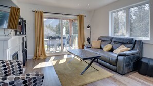 Un salon moderne avec un canapé en cuir, un fauteuil à motifs et une table basse en bois.