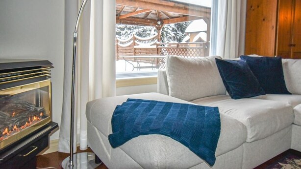 Ein gemütliches Wohnzimmer mit einem weißen Sofa, einer blauen Decke und einem Kaminofen.
