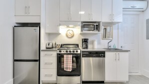 Une cuisine moderne dotée d’appareils électroménagers en acier inoxydable, de meubles blancs et d’une horloge murale.