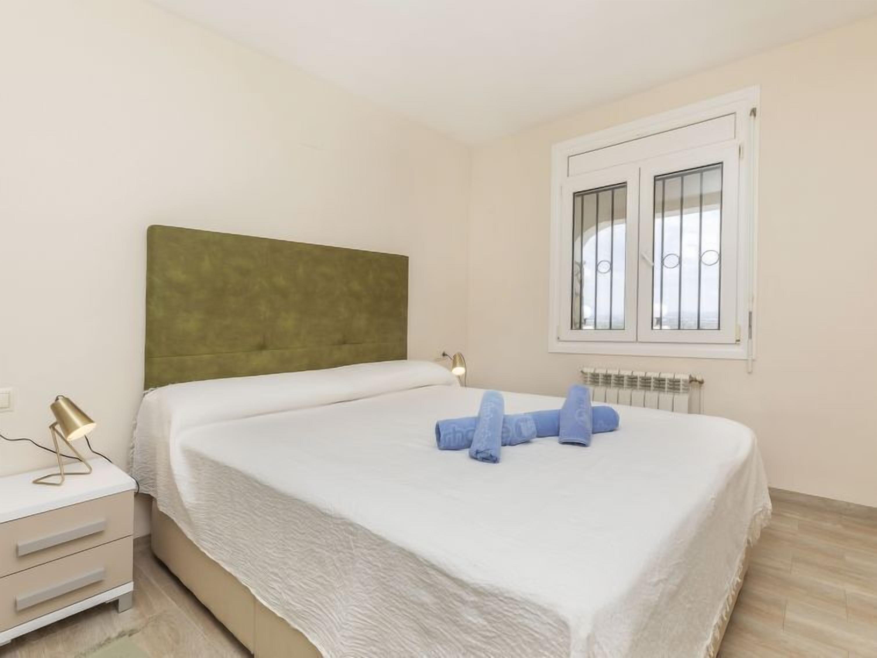 Une chambre à coucher avec un lit, une table de chevet, une lampe et une fenêtre avec des stores.