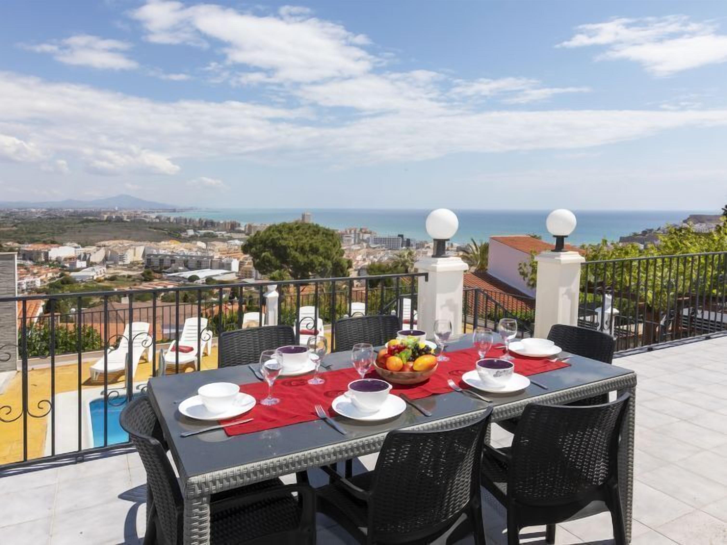 Une table à manger dressée pour quatre personnes, avec vue sur la mer et le paysage urbain.