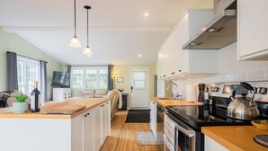 A modern kitchen with wooden countertops, stainless steel appliances, and pendant lighting.