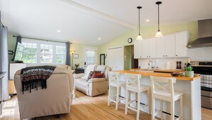 A modern kitchen with white cabinets, a wooden countertop, and a bar stool.