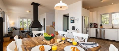 A modern kitchen with white cabinets, stainless steel appliances, and a dining area with a wooden table set for breakfast.