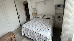 A bedroom with a bed, a bench, a hanging light fixture, and a wardrobe. - Pontaillac 30m Plage 1er Étage Villa (Royan)