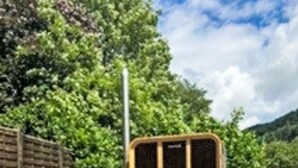 Un jardin avec un sentier de pierres menant à une structure en bois dotée de portes vitrées.