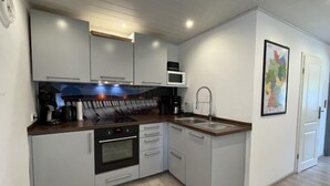 Une cuisine de taille réduite, avec des meubles blancs, un four à micro-ondes, une cuisinière et un évier.