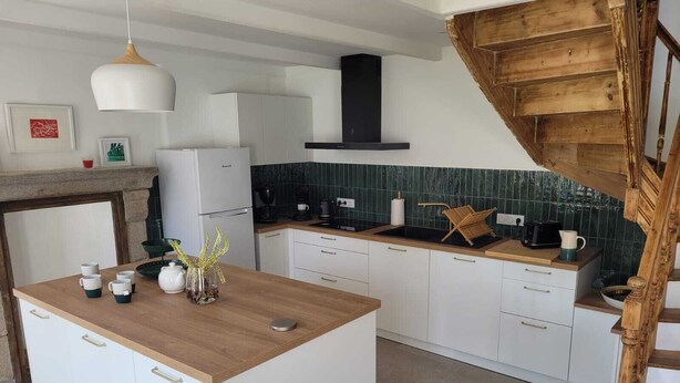 A modern kitchen with white cabinetry, a wooden island, and a green-tiled backsplash.