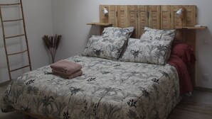 A bedroom with a bed, a wooden headboard, a skylight, and a hanging light fixture.