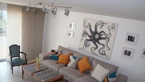 A living room with a sofa, armchairs, a coffee table, and a large abstract painting on the wall.