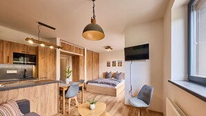 Un apartament modern amb cuina, zona de dinar i saló amb sofà i taula petita.