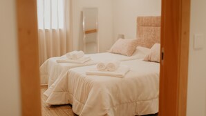 Ett hotellrum med två sängar, där handdukarna på varje säng är prydligt vikta, ett stort spegel och en neutral färgskala.