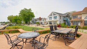 Een terras met buitenmeubilair, uitzicht op huizen en een gazon.