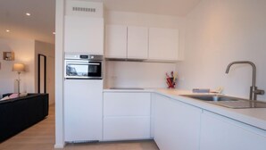 Cozinha moderna com armários brancos, forno de aço inoxidável e pia com torneira moderna.