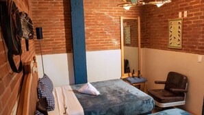 A room with two beds, a chair, a mirror, and a brick wall. - Antique Hotel (Mexico City)