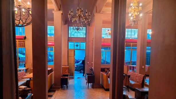 A hotel lobby with a marble floor, wooden columns, and chandeliers. - Antique Hotel (Mexico City)