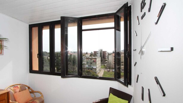 Ein Zimmer mit einem großen Fenster, einer Wanduhr und einem Sofa.