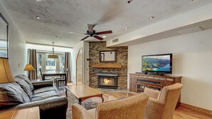 A modern living room with a fireplace, leather sofa, patterned armchairs, and a television. - Lodge at Mtn Village B261 | Ski-In/Out | Plaza View | PCMR | Pool | Hot Tub (Park City)