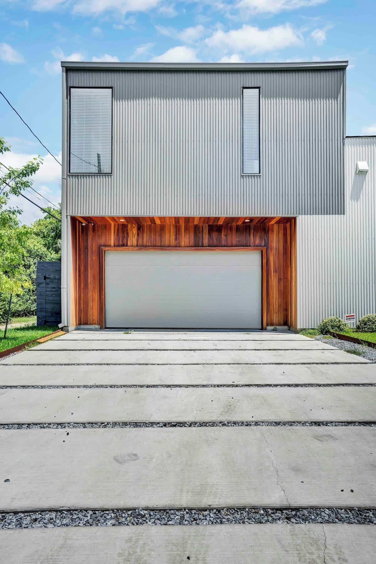 Un garage moderno con un'ampia porta, una parte inferiore in legno e una sezione superiore in metallo.