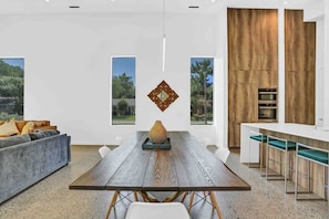 A modern kitchen with a wooden accent wall, a dining area with a wooden table, and a bar area with stools.