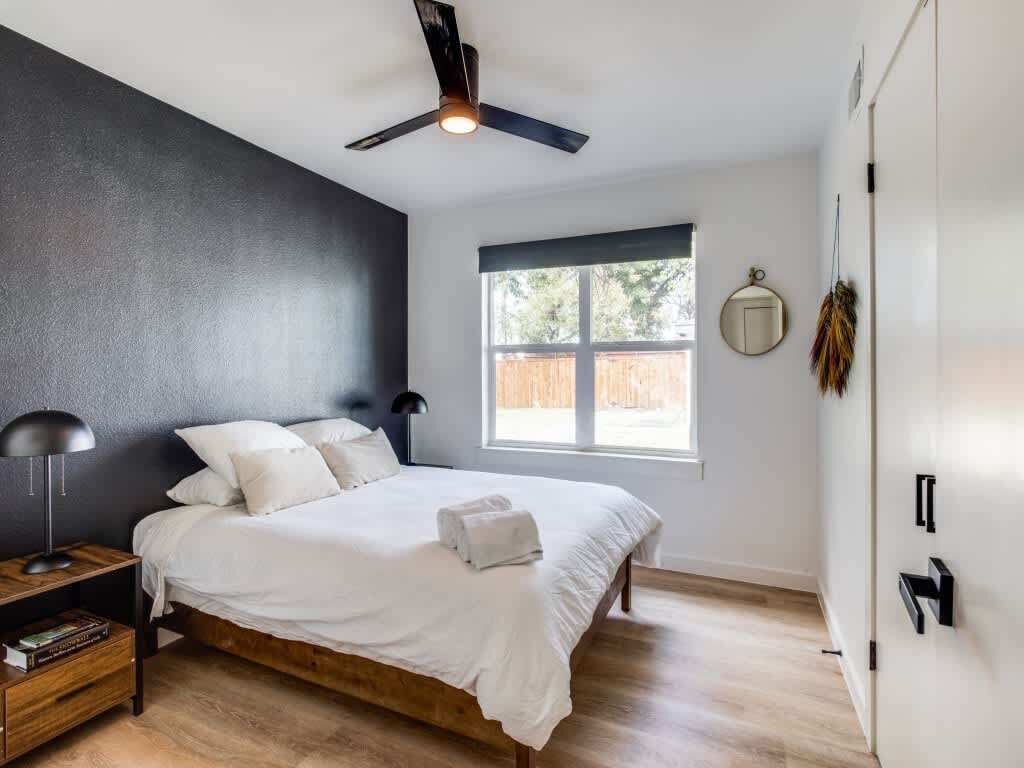 Une chambre à coucher comprenant un lit, un ventilateur de plafond, une fenêtre, une table de chevet et une armoire.