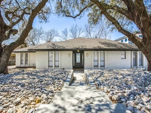 A single-story building with a front door, windows, and a paved driveway.